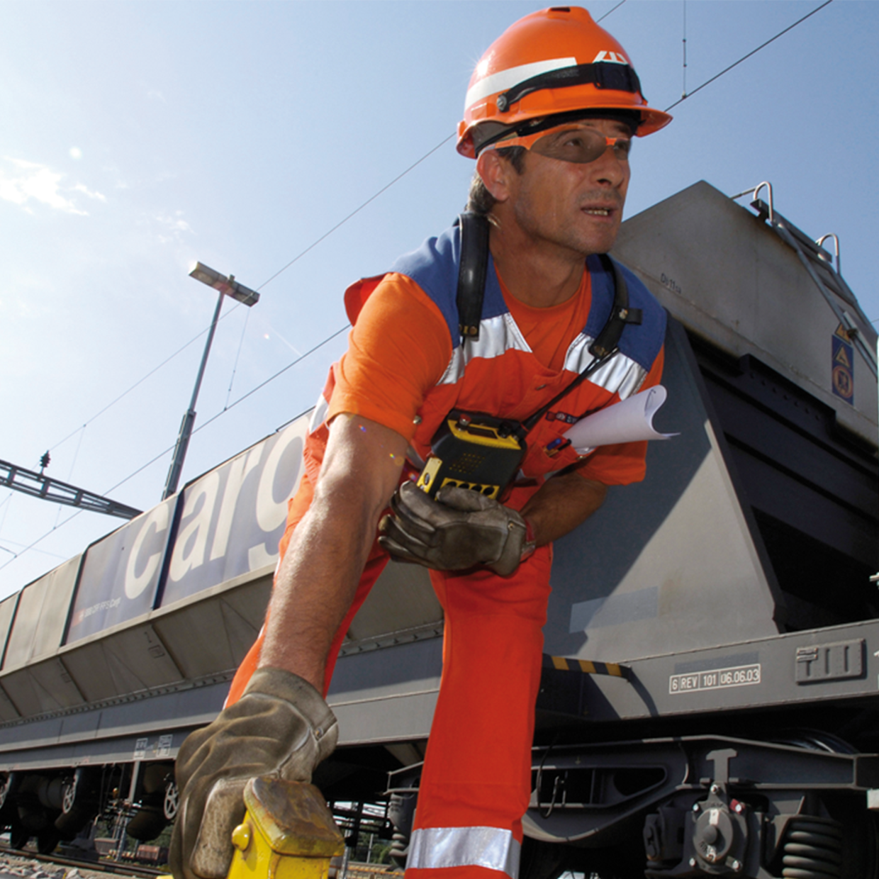 Ein Mitarbeitender von SBB Cargo und im Hintergrund ein Güterwagen.